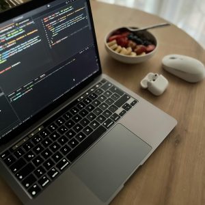 Home Cozy workspace featuring a laptop, mouse, and healthy fruit bowl on a wooden table.