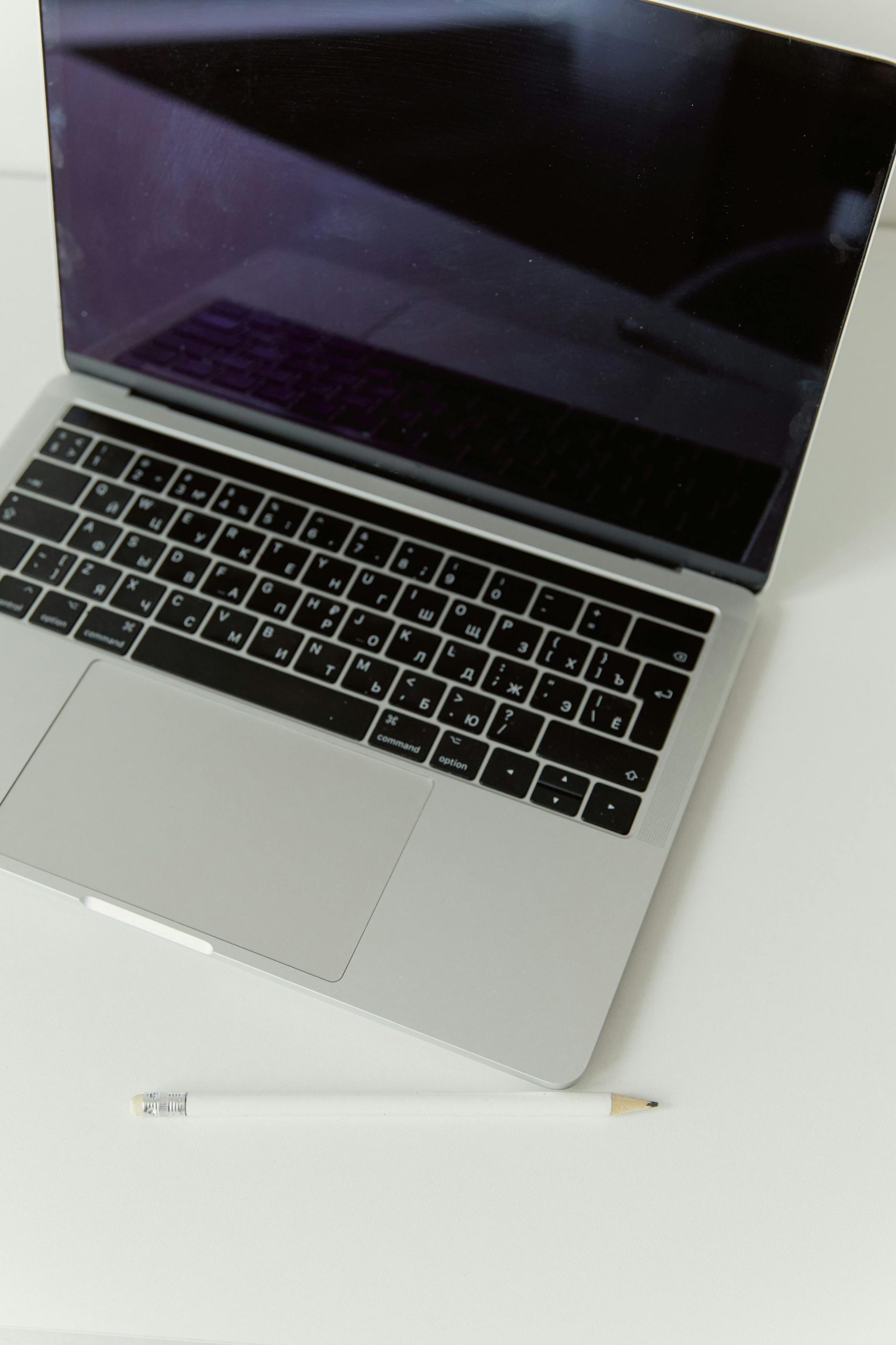 used macbooks A minimalist shot of a modern laptop and pencil on a clean, white desk.